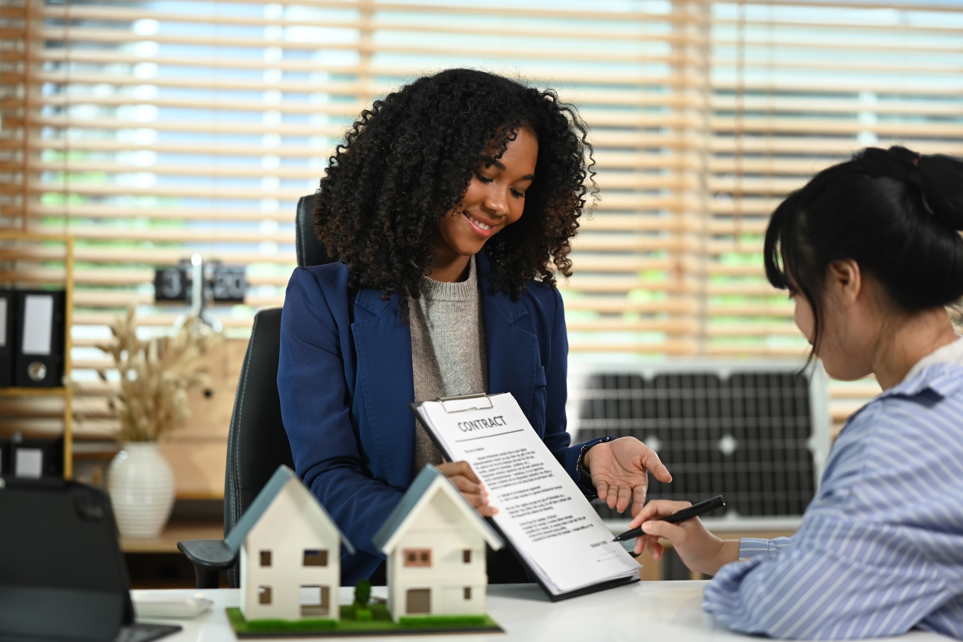 Professional real estate agent in suit pointing at contract document to client put a signature. Real estate and property insurance concepts